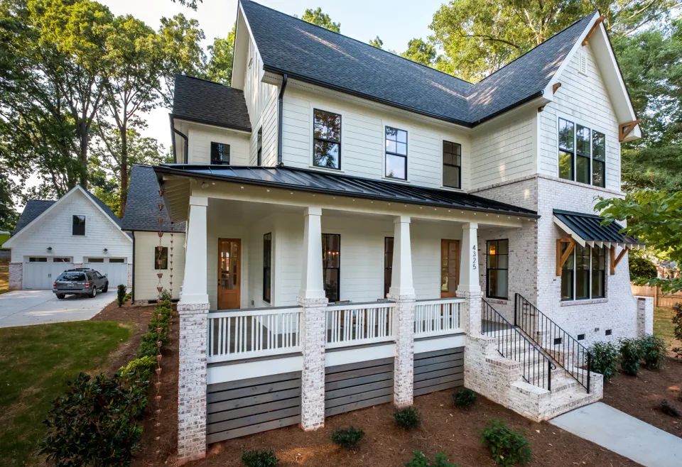 White home with a deep front porch, brick steps and a side entry.