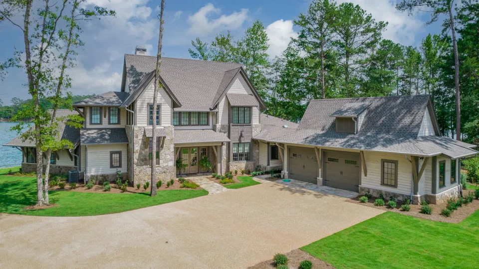 Lakeside home with stone columns, gray siding and an attached garage.