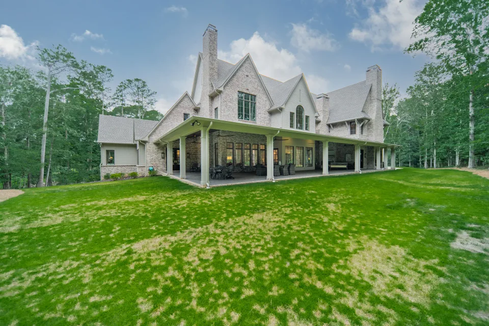 Brick home with a deep rear porch overlooking a broad lawn.