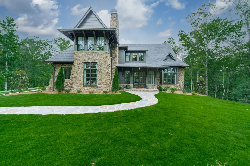 Stone and gray sided home with a tall gabled entry and curved front path.