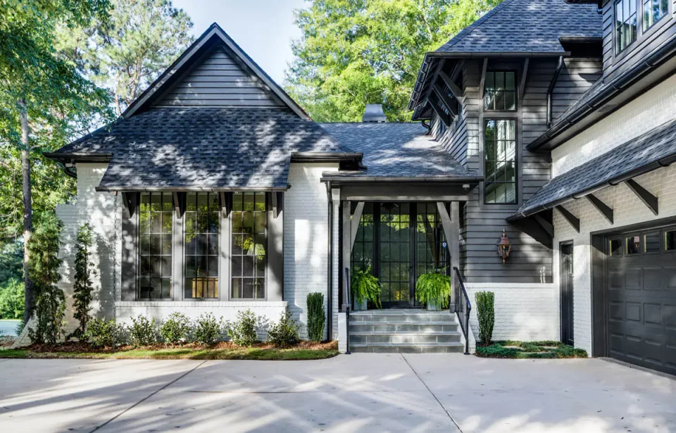 Renovated home with a stone entry and dark framed windows facing the drive.