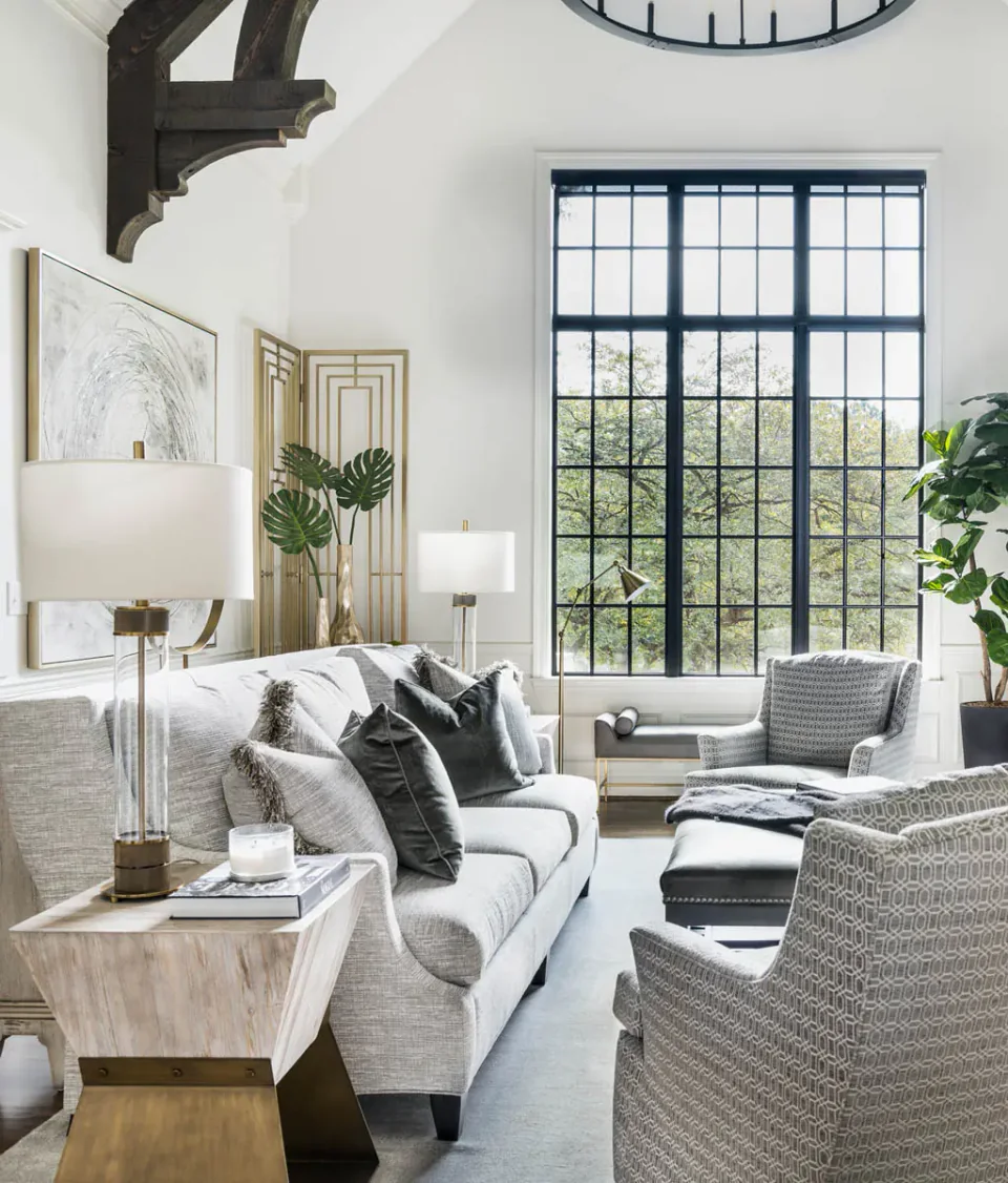 Living room with exposed ceiling beams, upholstered seating and a large window.